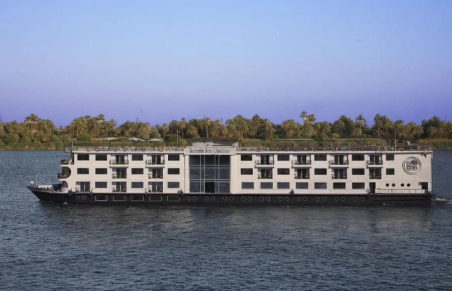 The Sonesta Star Goddess Nile cruise ship sailing on the Nile River, showcasing its multi-story design and numerous balconies for passengers.
