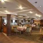 The elegant and spacious restaurant on the Sonesta Star Goddess Nile cruise ship, set with tables and a buffet station for a delightful dining experience.