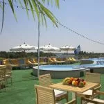 The sunny and spacious sundeck of the Sonesta Star Goddess Nile cruise ship, with a pool, lounge chairs, and comfortable seating areas for relaxation.