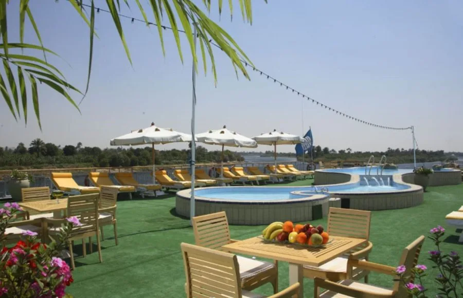 The sunny and spacious sundeck of the Sonesta Star Goddess Nile cruise ship, with a pool, lounge chairs, and comfortable seating areas for relaxation.
