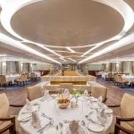 The elegant and spacious dining room on the Sonesta Sun Goddess Nile cruise ship, set with tables and chairs ready for a delicious meal.