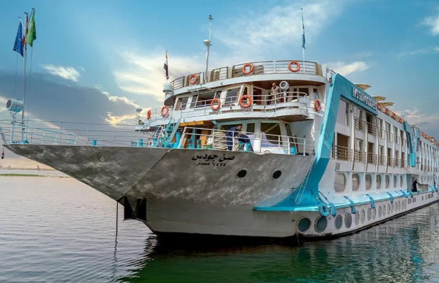 The elegant Sonesta Sun Goddess Nile cruise ship, a Sonesta Sun Goddess Nile River Cruise, is shown sailing majestically on the Nile River under a clear sky.