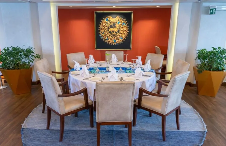 An elegantly set dining table in the restaurant of the Sonesta Sun Goddess Nile River Cruise, featuring a decorative centerpiece and comfortable chairs.