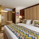 A luxurious suite on the Sonesta Sun Goddess Nile cruise ship, with a king-sized bed and a view into a stylish bathroom.