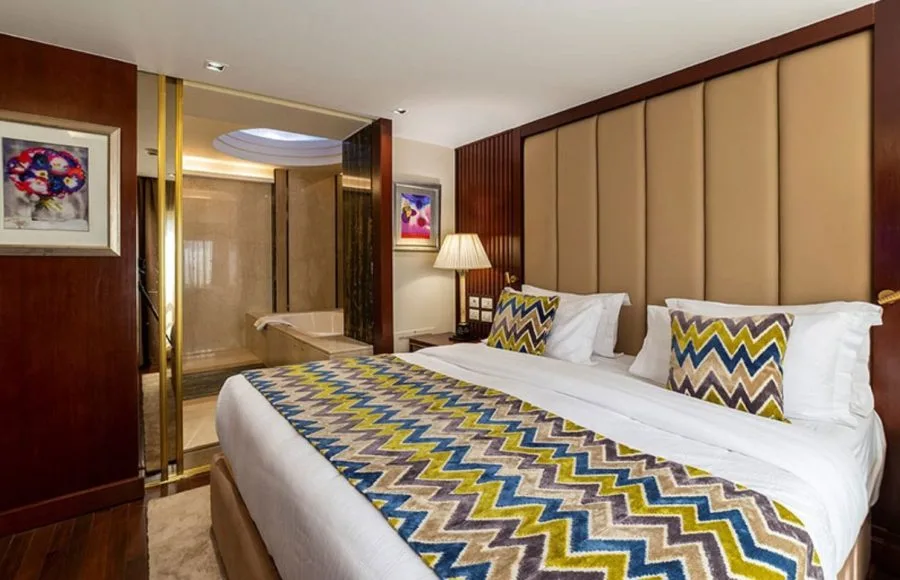 A luxurious suite on the Sonesta Sun Goddess Nile cruise ship, with a king-sized bed and a view into a stylish bathroom.
