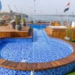 The sparkling swimming pool and jacuzzi on the sun deck of the Sonesta Sun Goddess Nile River Cruise ship, with the tranquil Nile in the background.