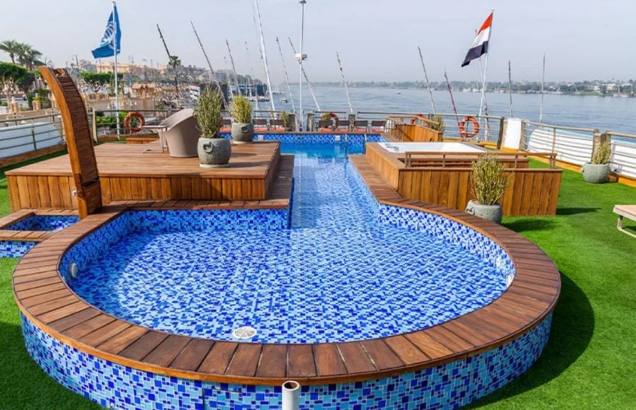 The sparkling swimming pool and jacuzzi on the sun deck of the Sonesta Sun Goddess Nile River Cruise ship, with the tranquil Nile in the background.