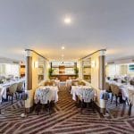 The elegant dining room of the Tamr Henna Nile Cruise Ship features beautifully set tables with crisp white linens and large windows offering scenic views of the Nile River