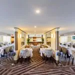 The elegant dining room of the Tamr Henna Nile Cruise Ship features beautifully set tables with crisp white linens and large windows offering scenic views of the Nile River