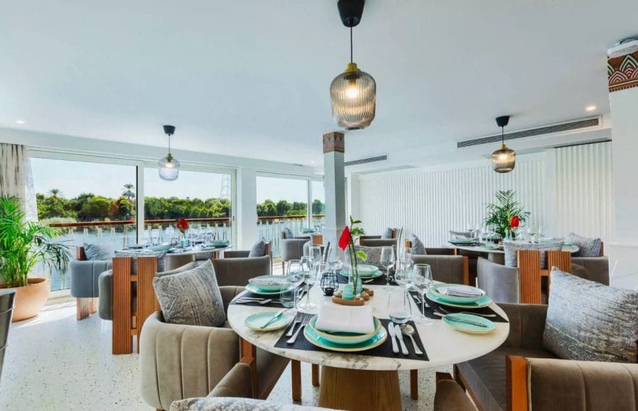 The elegant and modern dining area aboard the MS Tamr Henna Nile Cruise offers stylish marble tables plush velvet chairs and panoramic views of the Nile River as you sail