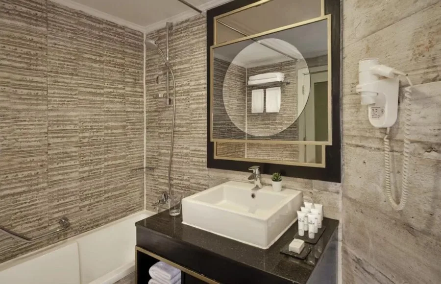 A modern, well-appointed bathroom on the MS Tulip Nile Cruise featuring a bathtub, contemporary vanity, stylish mirror, and textured wall tiles.