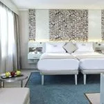 A bright and inviting cabin on the MS Tulip Nile Cruise with twin beds, modern decor featuring hieroglyphics, and a cozy seating area with a fruit platter.