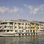 The luxurious, multi-deck MS Tulip Nile Cruise ship sails majestically on the calm waters of the Nile under a bright blue sky.