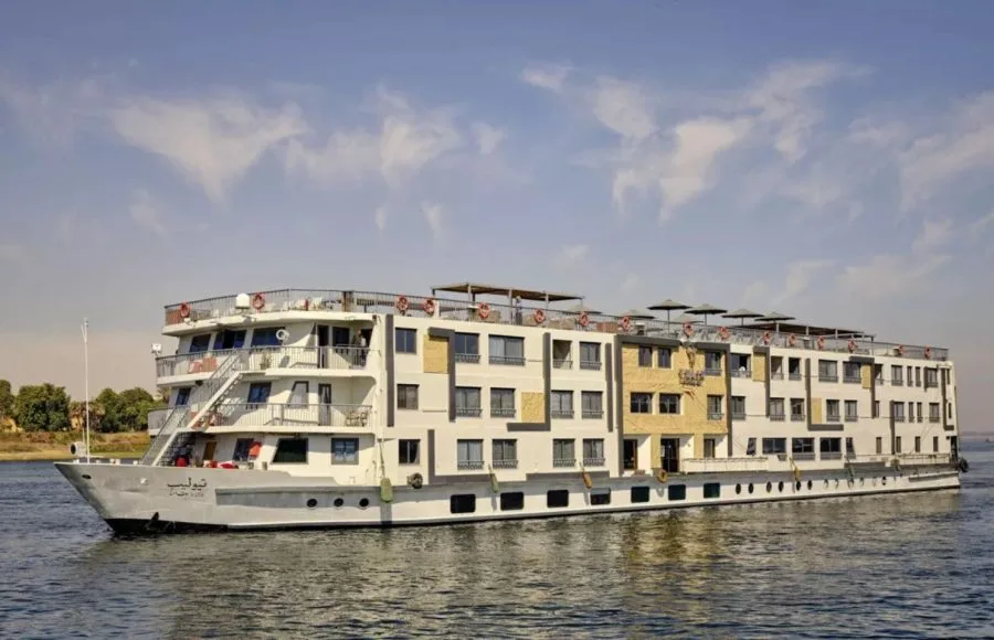 The luxurious, multi-deck MS Tulip Nile Cruise ship sails majestically on the calm waters of the Nile under a bright blue sky.