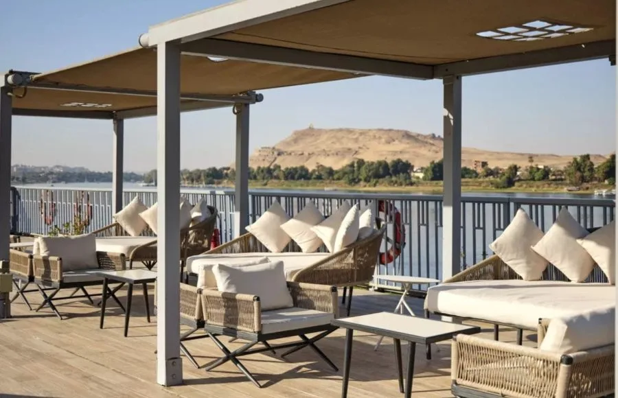 Relax on the beautiful sun deck lounge of the MS Tulip Nile Cruise, featuring comfortable seating and a spectacular panoramic view of the river and desert landscape.
