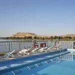 The refreshing swimming pool deck on the MS Tulip Nile Cruise offers sun loungers and stunning views of the desert hills lining the riverbanks.