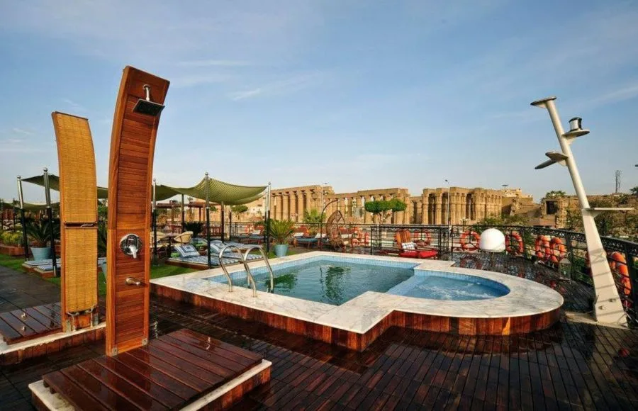 The swimming pool on the sun deck of the MS Mayfair Nile Cruise with a view of an ancient temple.