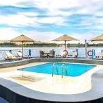 Experience luxury aboard the Moondance Nile Cruise, featuring a stunning pool deck with lounge chairs and umbrellas, offering breathtaking views of the river.