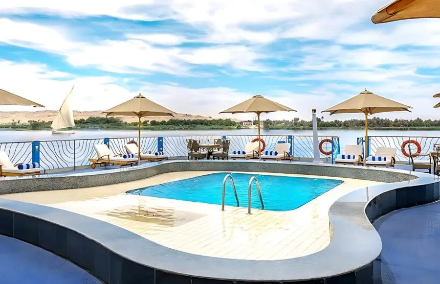 Experience luxury aboard the Moondance Nile Cruise, featuring a stunning pool deck with lounge chairs and umbrellas, offering breathtaking views of the river.