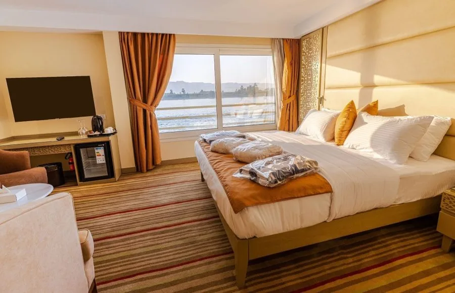 Nebu Nile Cruise suite with Nile view, large bed, and TV.