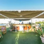 An outdoor bar and lounge area on the sun deck of the Blue Shadow IV, with a covered canopy and comfortable seating.