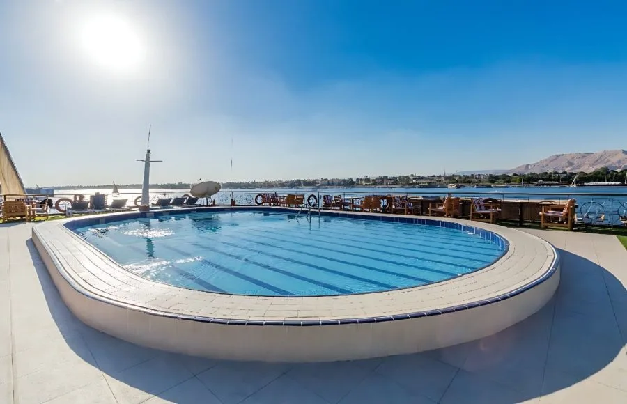 The swimming pool on the sun deck of the Blue Shadow IV, with a serene view of the Nile River.
