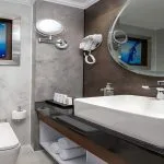 A contemporary and elegant bathroom aboard the Sindbad Nile Cruise, featuring a sleek basin, modern mirror, and a calming blue artwork.