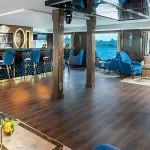 The inviting lounge bar on the Sindbad Nile cruise, with plush blue armchairs, a stylish bar, and large windows offering scenic views of the river.