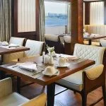 The elegant dining room aboard the Sindbad Nile Cruise, set with pristine tables and chairs, offering panoramic views of the river while you enjoy your meal.