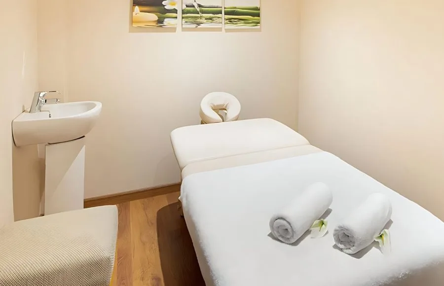A tranquil spa treatment room aboard the Sindbad Nile Cruise, featuring a massage table, sink, and calming artwork.