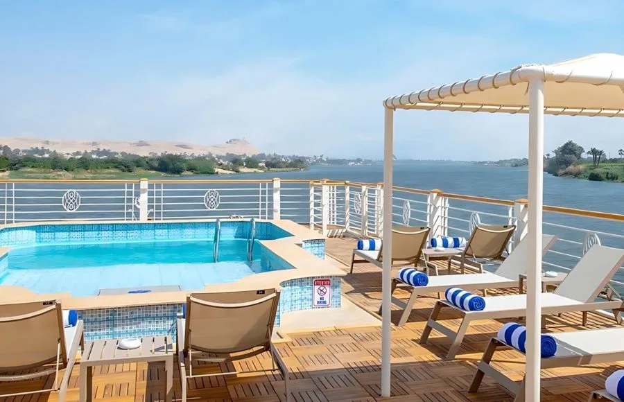 The inviting sun deck of the Sindbad Nile cruise, featuring a sparkling swimming pool, comfortable loungers, and expansive views of the Nile River landscape.