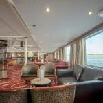A luxurious and inviting lounge on the Sonesta Star Goddess Nile cruise ship, featuring comfortable seating and large windows with scenic views of the Nile River.