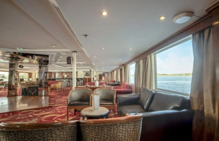 A luxurious and inviting lounge on the Sonesta Star Goddess Nile cruise ship, featuring comfortable seating and large windows with scenic views of the Nile River.