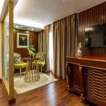 A luxurious suite on the Sonesta Sun Goddess Nile cruise ship, featuring a comfortable bed, a cozy seating area, and elegant wood paneling.