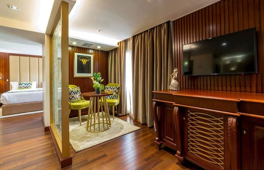 A luxurious suite on the Sonesta Sun Goddess Nile cruise ship, featuring a comfortable bed, a cozy seating area, and elegant wood paneling.