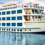 The majestic Kon Tiki Nile cruise ship sailing on the river with its sun deck and cabins visible.