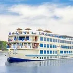 The majestic Kon Tiki Nile cruise ship sailing on the river under a blue sky, showcasing its multiple decks and spacious cabins