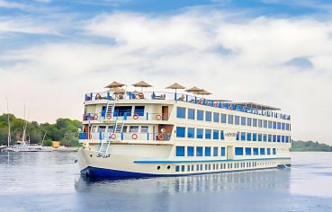 The majestic Kon Tiki Nile cruise ship sailing on the river under a blue sky, showcasing its multiple decks and spacious cabins
