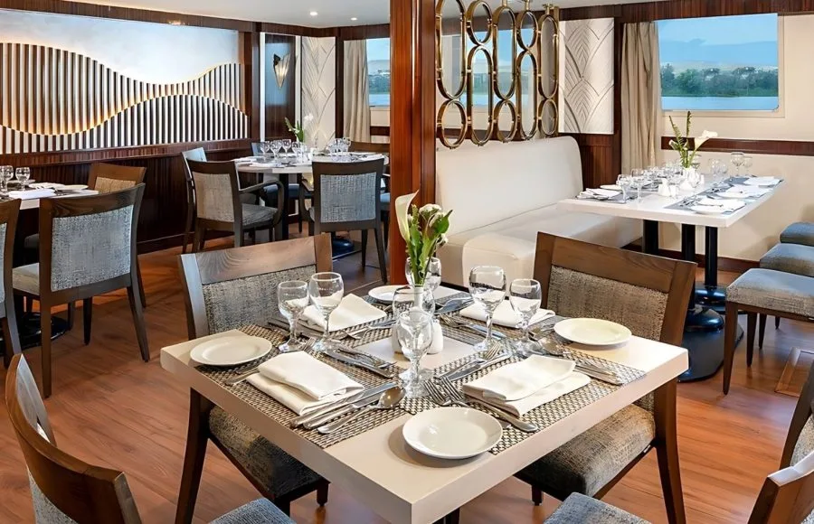 The elegant dining area on the Kon Tiki Nile cruise with beautifully set tables and large windows offering river views.