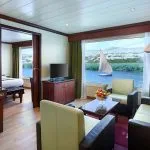 The spacious and elegant suite on the Kon Tiki Nile cruise featuring a comfortable living area, bedroom access, and a large window with river views.