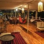 A nighttime view of the outdoor seating and dining deck on the Abundance Dahabiya houseboat.