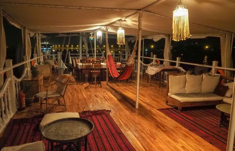 A nighttime view of the outdoor seating and dining deck on the Abundance Dahabiya houseboat.