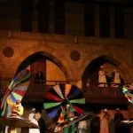 Dancers lifting colorful multi-layered skirts vertically while spinning in Cairo.