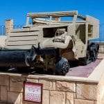 American M3 Half-track troop carrier on display at the El Alamein War Museum against a backdrop of the Mediterranean Sea.