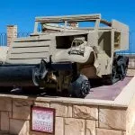 American M3 Half-track troop carrier on display at the El Alamein War Museum against a backdrop of the Mediterranean Sea.