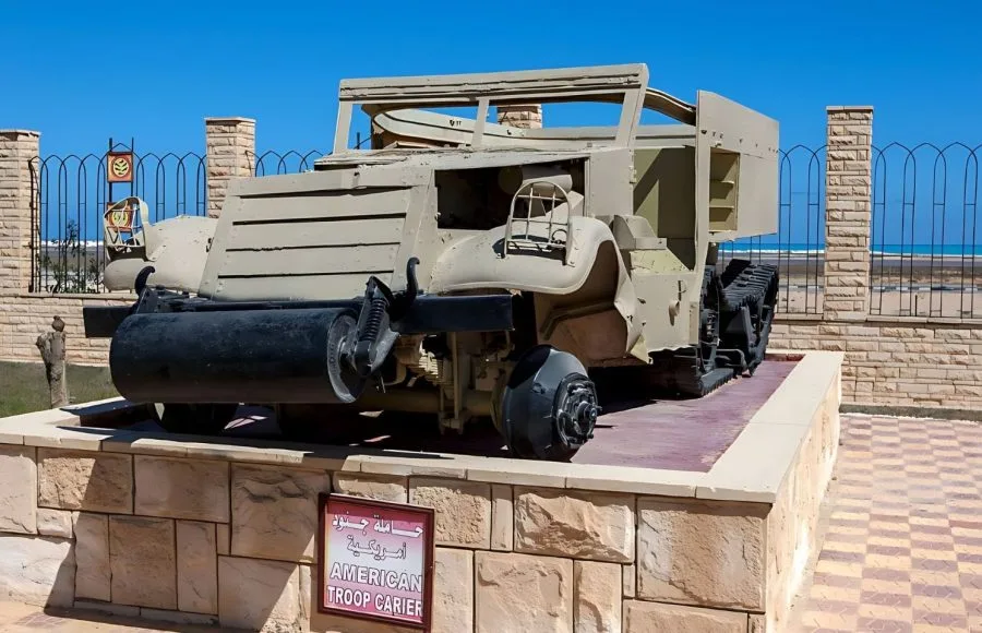 American M3 Half-track troop carrier on display at the El Alamein War Museum against a backdrop of the Mediterranean Sea.