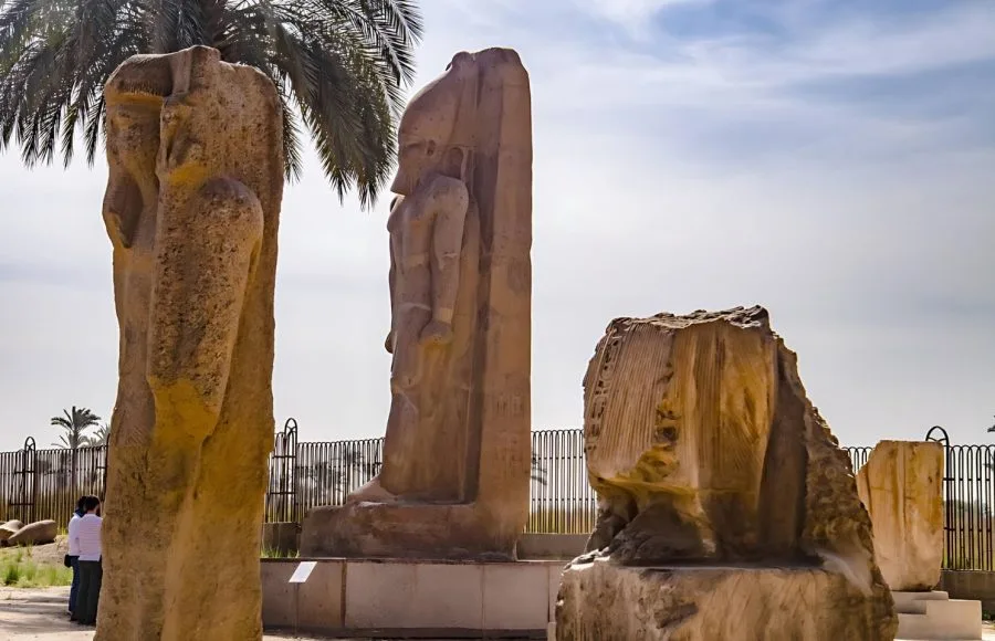 Monumental statues of Pharaoh Ramesses II standing at the ruins of ancient Memphis, Egypt.