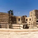 The ancient Roman ruins of the Babylon Fortress in Old Cairo, showing the curved brick walls and protective railing.