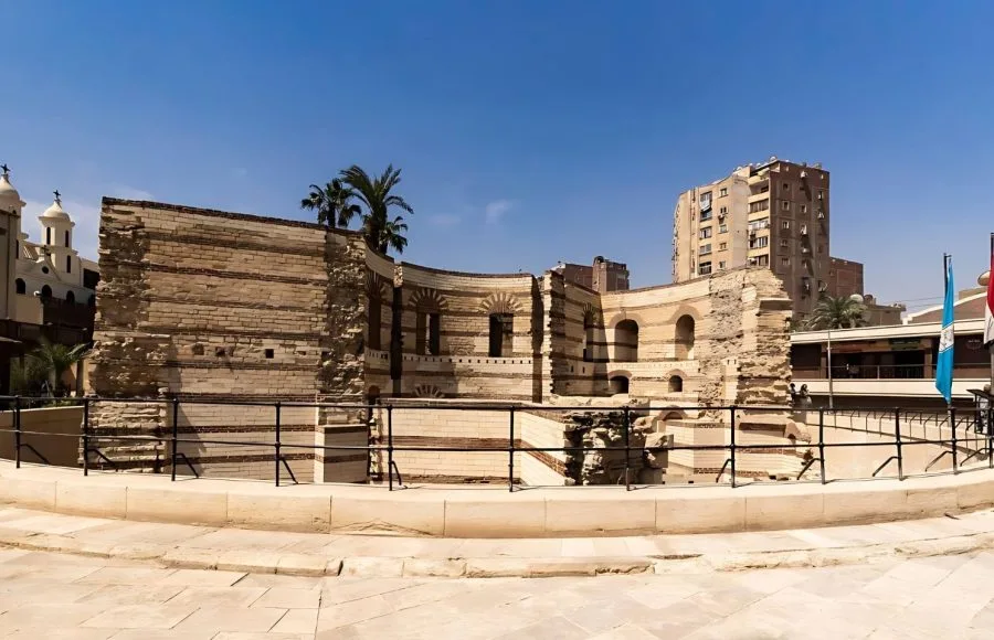 The ancient Roman ruins of the Babylon Fortress in Old Cairo, showing the curved brick walls and protective railing.
