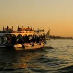 A white passenger boat cruising the Nile River during a golden sunset in Cairo.